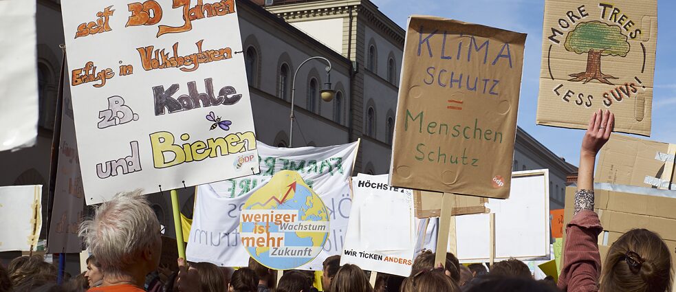 Eine Demonstrationen zum Klima ist zu sehen. Viele Plakate werden in die Luft gehalten.