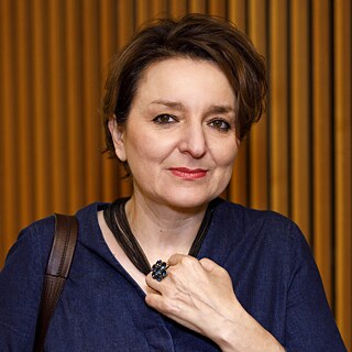 Square image of Eva Illouz against a brown backdrop; she wears short dark hair and holds a glas in her left hand © Geisler-Fotopress © picture alliance Portrait of Eva Illouz