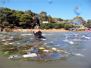 A woman and a man in rubbish filled water, one swimming, one standing up.