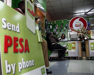 Uma loja de celulares M-Pesa na capital do Quênia, Nairóbi. M-PESA é a plataforma de “dinheiro móvel” da operadora de telefonia móvel Safaricom, que permite transferências financeiras através de telefones celulares. O Quênia é o primeiro país do mundo a utilizar esse serviço, que ajuda a transferir pequenos montantes de dinheiro para pagamento de bens e serviços ou para parentes que vivem em pequenos vilarejos, sem envolver bancos. 