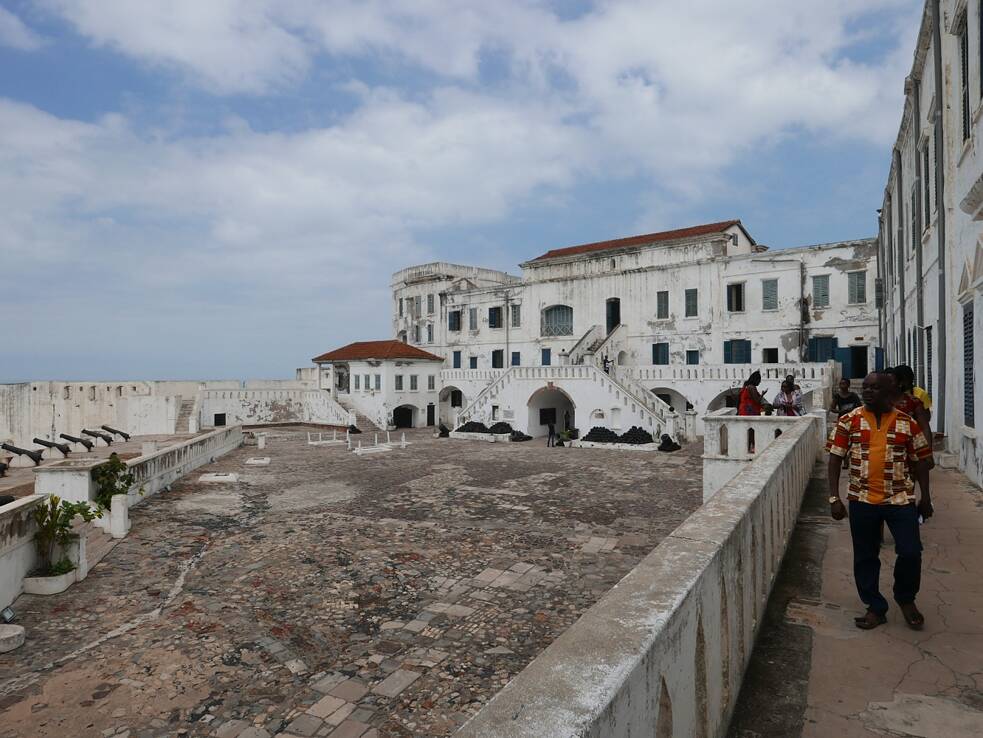 Historia colonial: El Castillo de la costa del Cabo, en Ghana, sirvió como una base muy importante para el comercio de esclavos. Hoy en día, la antigua fortaleza es un gran museo sobre la historia de la trata de esclavos en la antigua Costa de Oro y, desde 1979, pertenece al Patrimonio de la Humanidad de la Unesco. En la Costa de Oro de África occidental, Dinamarca mantuvo en los siglos XVII y XVIII numerosas bases y fortalezas, que se designan en conjunto como la Costa de Oro danesa, o bien, como la Guinea danesa. El Castillo de la costa del Cabo es uno, de un aproximado de treinta y cinco fuertes históricos de la costa de Ghana.  Así como la mayoría de los otros fuertes de la llamada "Costa de Oro“, según Wikipedia, el Castillo de la costa del Cabo funcionó como prisión para los originarios que habían sido capturados para ser vendidos y transportados como esclavos a las colonias europeas del Norte y del Sur de América, quienes con frecuencia debían esperar durante meses en las mazmorras de los fuertes a la espera del siguiente barco de esclavos, antes de que finalmente los llevaran a través de un estrecho pasillo de sótano hasta la playa para embarcarlos.