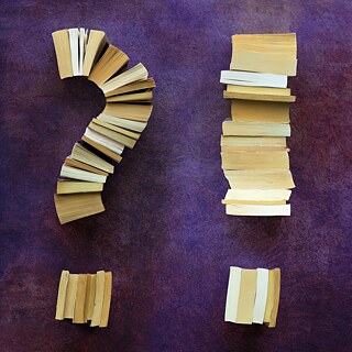 Übereinandergestapelte Bücher, die ein ? und ein ! bilden