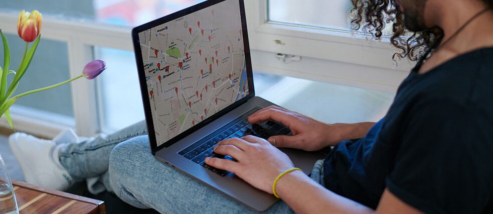 Ein junger Man sieht auf eine Karte auf seinem Laptop.