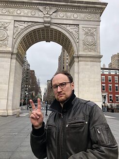 Nik poses in a deserted Washington Square Park with 5th Avenue in the background
