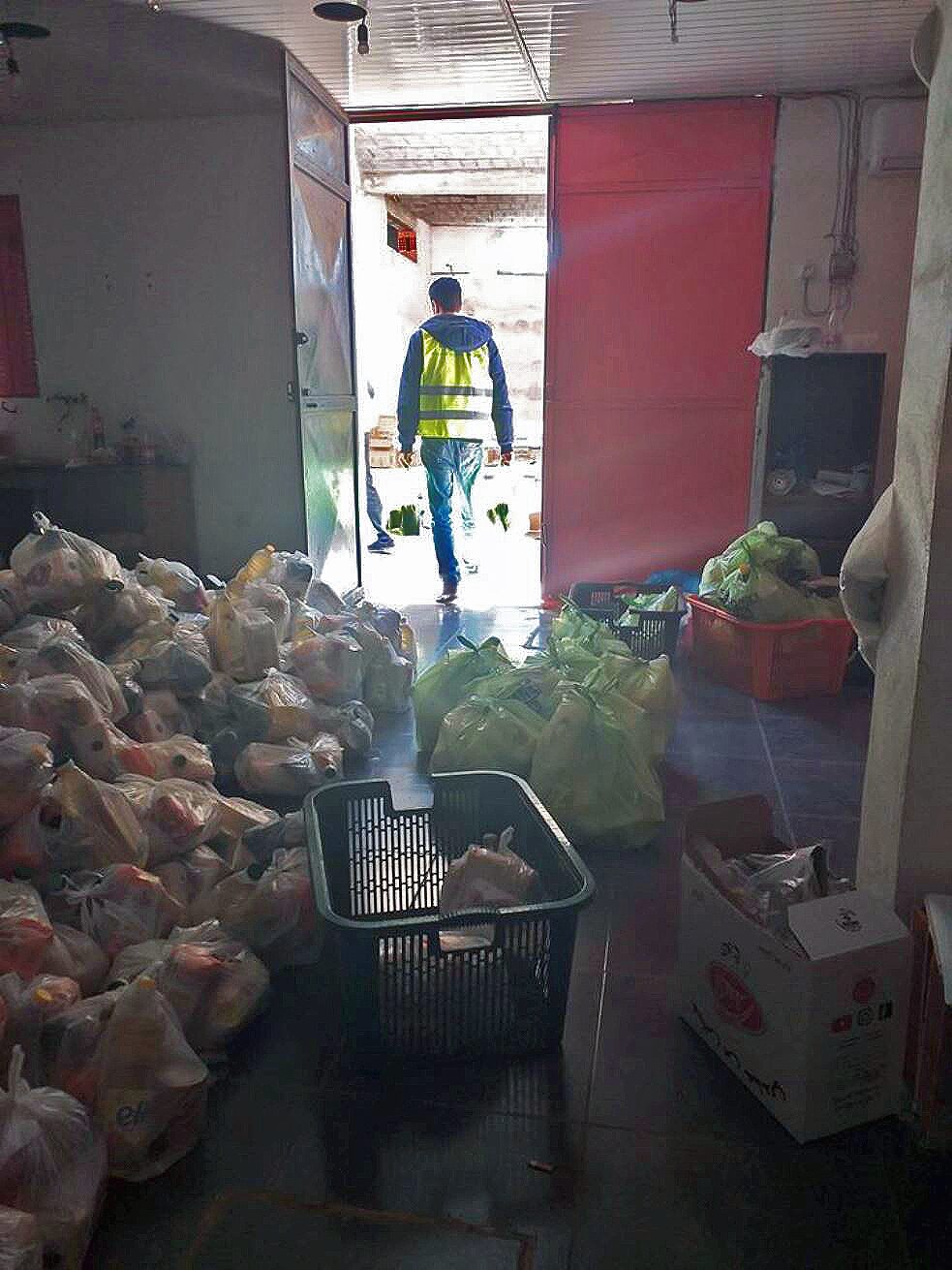 Image of a room filled with plastic bags of food and a man walking through the door.