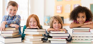 Kinder lehnen auf Bücherstapeln