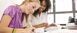 Zwei Sprachkursteilnehmerinnen machen sich Notizen.