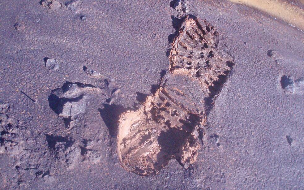 Foto von einem Schuhabdruck in feuchter schwarzer Erde