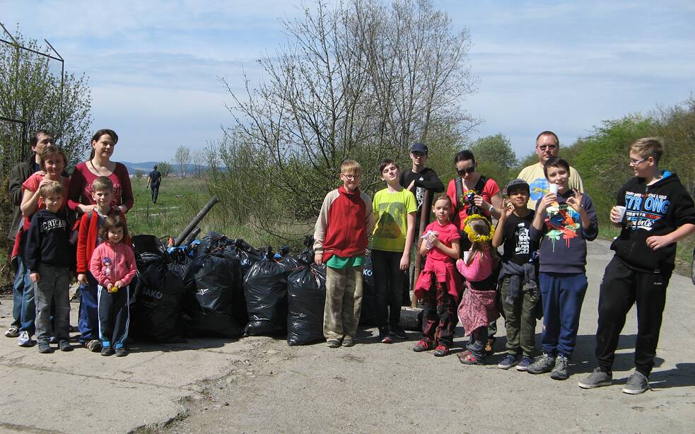 Eine Gruppe Menschen vor einer Menge schwarzer Müllsäcke.