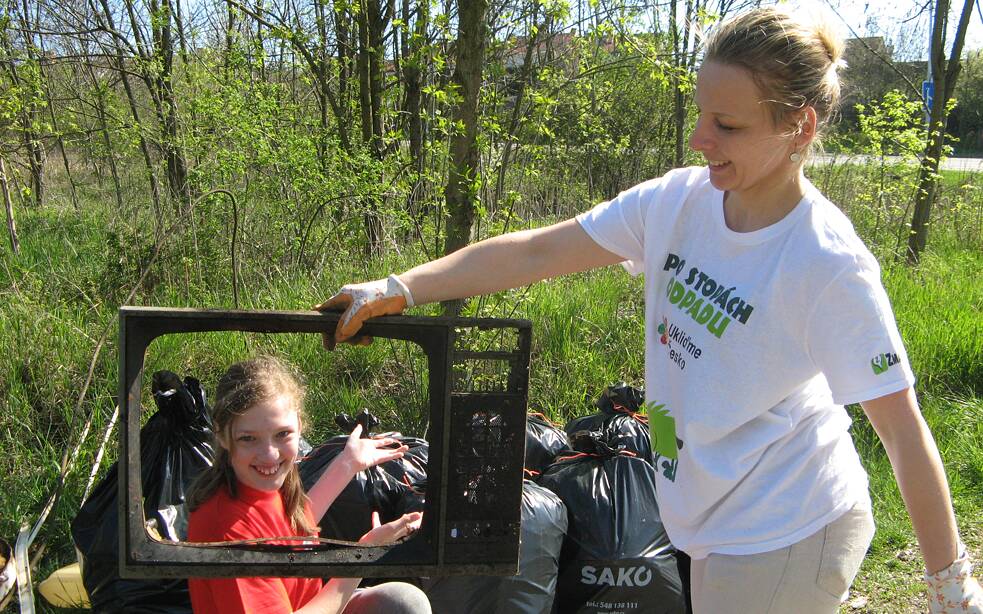 Frau hält einen alten Fernsehrahmen vor ein lächelndes Mädchen.