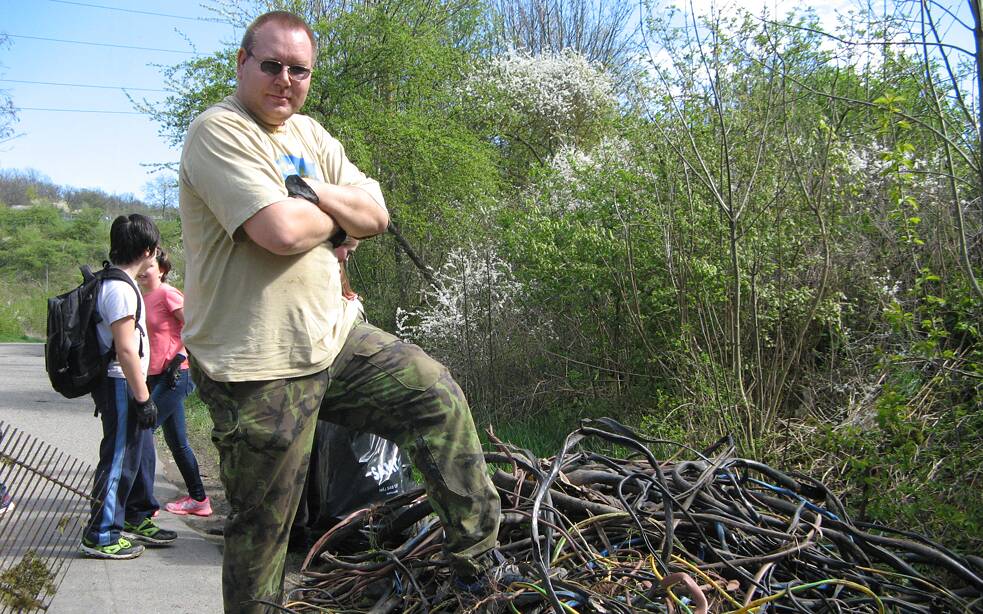 Mann steht stolz vor einem großen Berg alter Kabel.