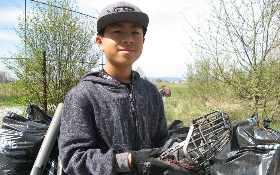 Junge hält eine Schutzmaske in die Kamera.