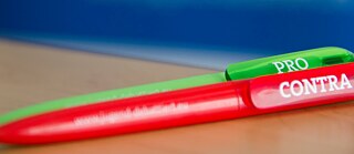 Roter Stift und grüner Stift auf dem Tisch am blauen Hintergrund ©  © Jugend debattiert in MOSE Jugend debattiert