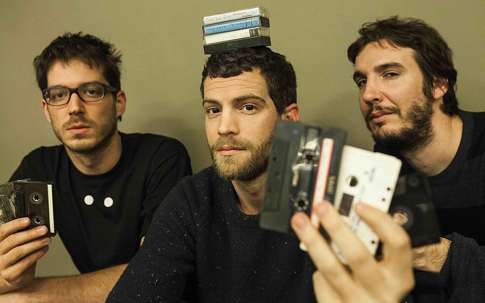 Foto von drei jungen Männern mit Kassetten in der Hand.