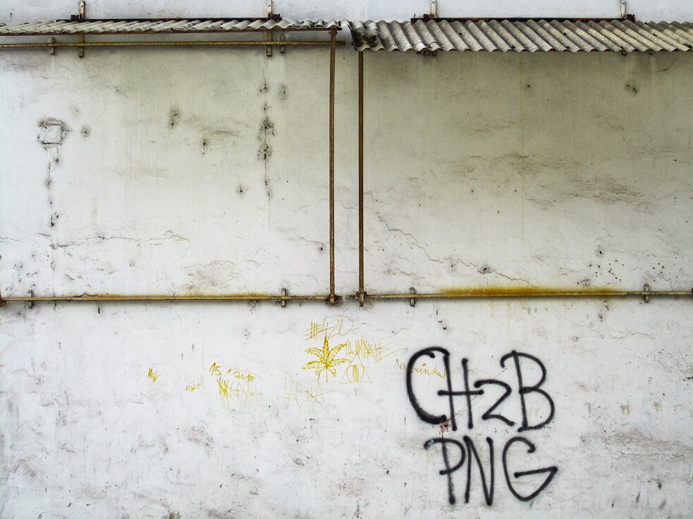 Graffiti an schmutziger weißer Hauswand.