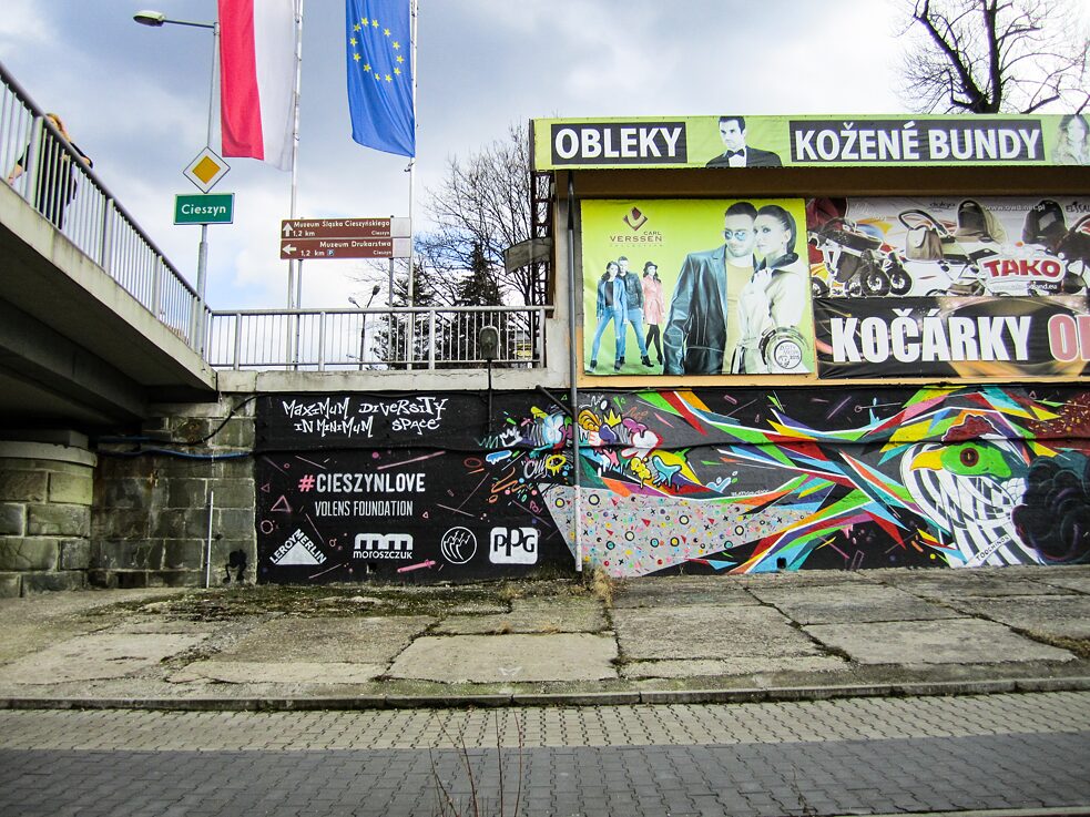 Foto von einer Straße mit einer Wand mit Werbung und Graffiti