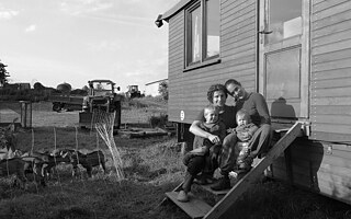 Junge Familie sitzt vor mobilem Eigenheim.