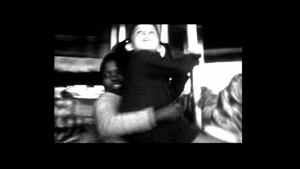 Colonial history – The image is a screenshot from the film “A Memory in Three Acts”. It shows a black child and a white child on a merry-go-round.