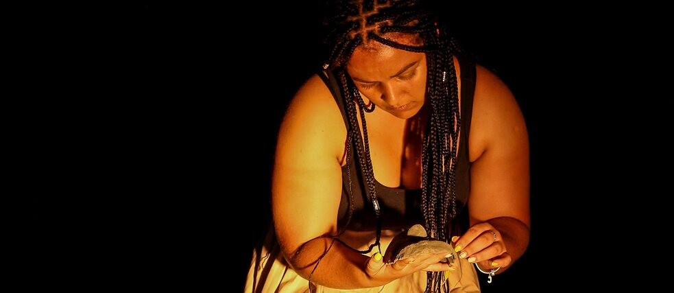 Trixie Munyama looks at a piece of clay in her hand during a performance. 