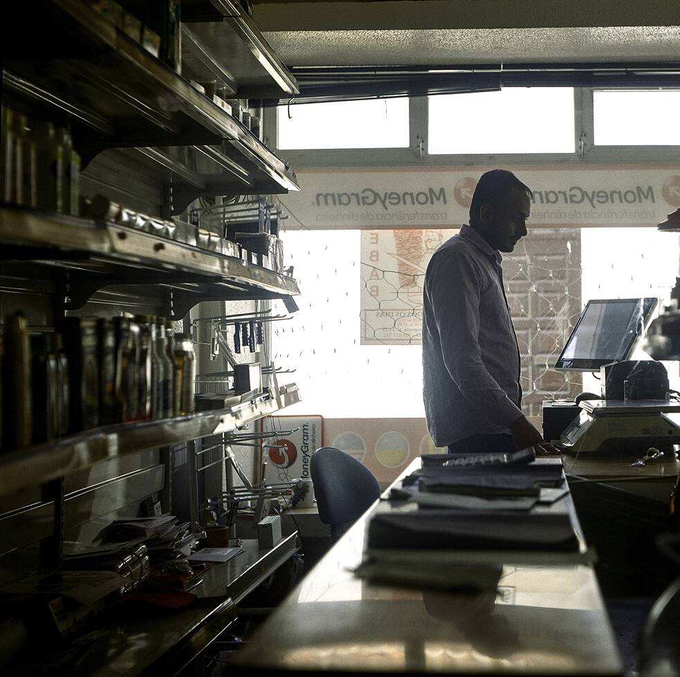 Junger Inder steht in einem Laden hinter der Kasse.