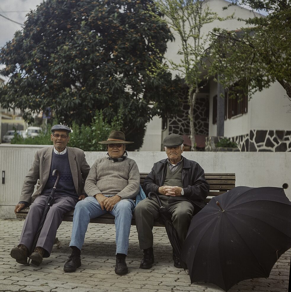 Foto von drei älteren Herren auf einer Bank.