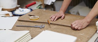 Someone is working at a workbench. You can see a ruler, a caliper gauge and adhesive tape.