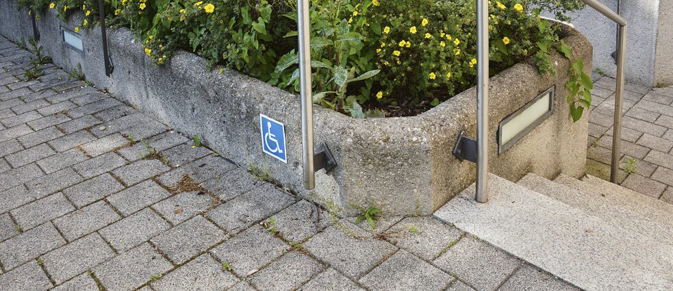 Man sieht eine Hebevorrichtung mit einem blau-weißen Aufkleber, der ein Symbol mit einem Rollstuhlfahrer zeigt.