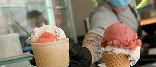 Eisverkaufer mit Mund-Nasen-Schutz in der Corona-Krise in einem Eiscafé 
