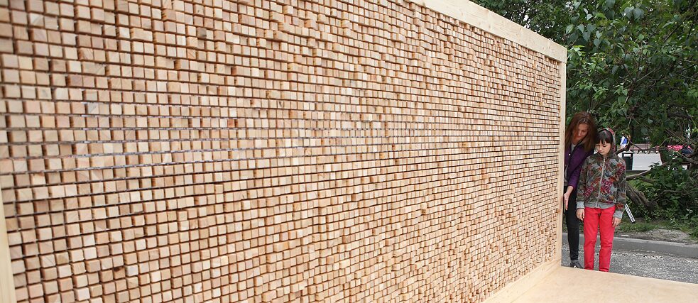Die „Verschwindende Wand“ ist eine Installation aus einem Plexiglasgerüst, in das rund 6.000 Holzklötze mit Zitaten eingesetzt werden.
