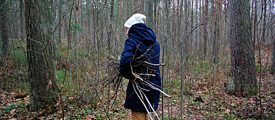 Eine Frau sammelt Zweige im Herbstwald