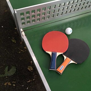Zwei Tischtennisschläger und ein Ball liegen auf einer Tischtennis-Platte in einem Stadtpark in München.