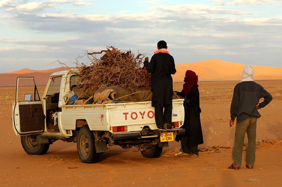  Beduínos carregando um jipe com lenha no deserto do Saara, Líbia. 