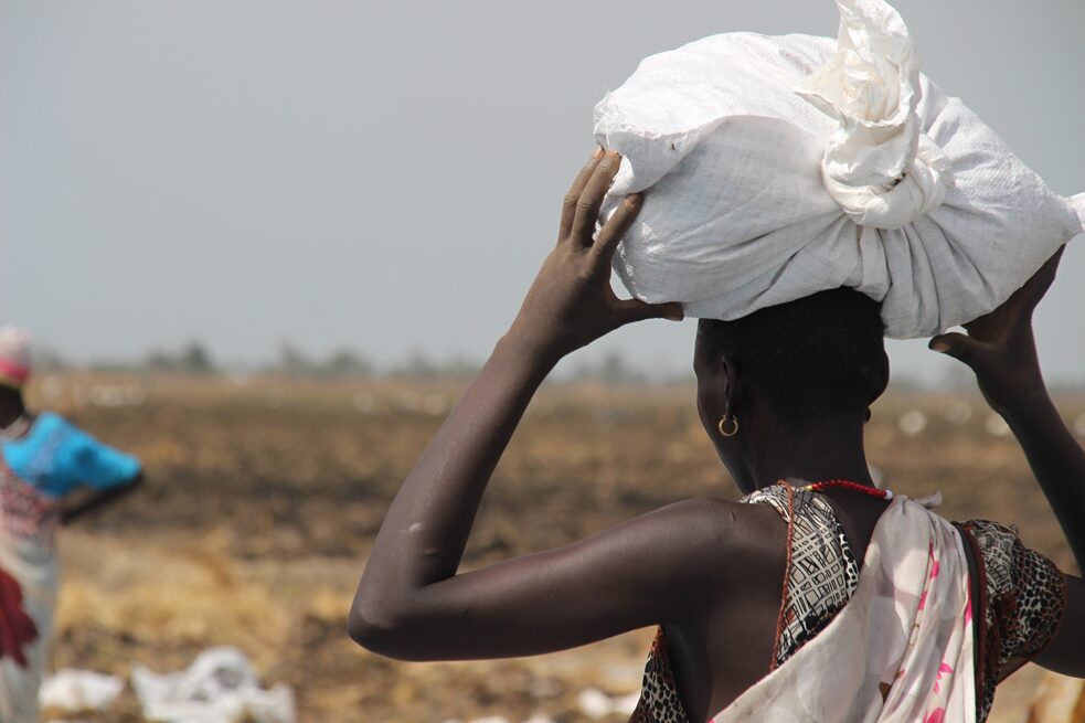 Latitude – Eine Frau trägt auf ihrem Kopf einen Sack Hilfsgüter – Linsen und Bohnen, aufgenommen am 24. März 2017 im Ort Ganyliel im Bundesstaat Unity, dem damals am meisten vom Hunger betroffenen Gebiet im Südsudan
