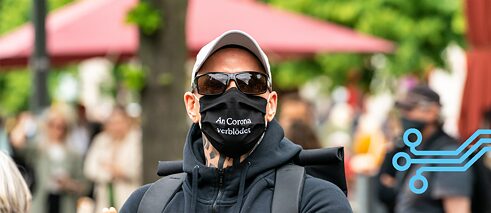Fotografija izbliza čoveka sa higijenskom maskom sa natpisom „Zaglupeo od korone“