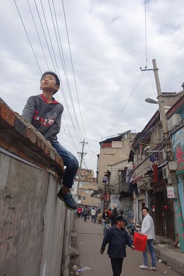 老城区长堤街的孩子骑坐在墙头打望拆迁建设工地