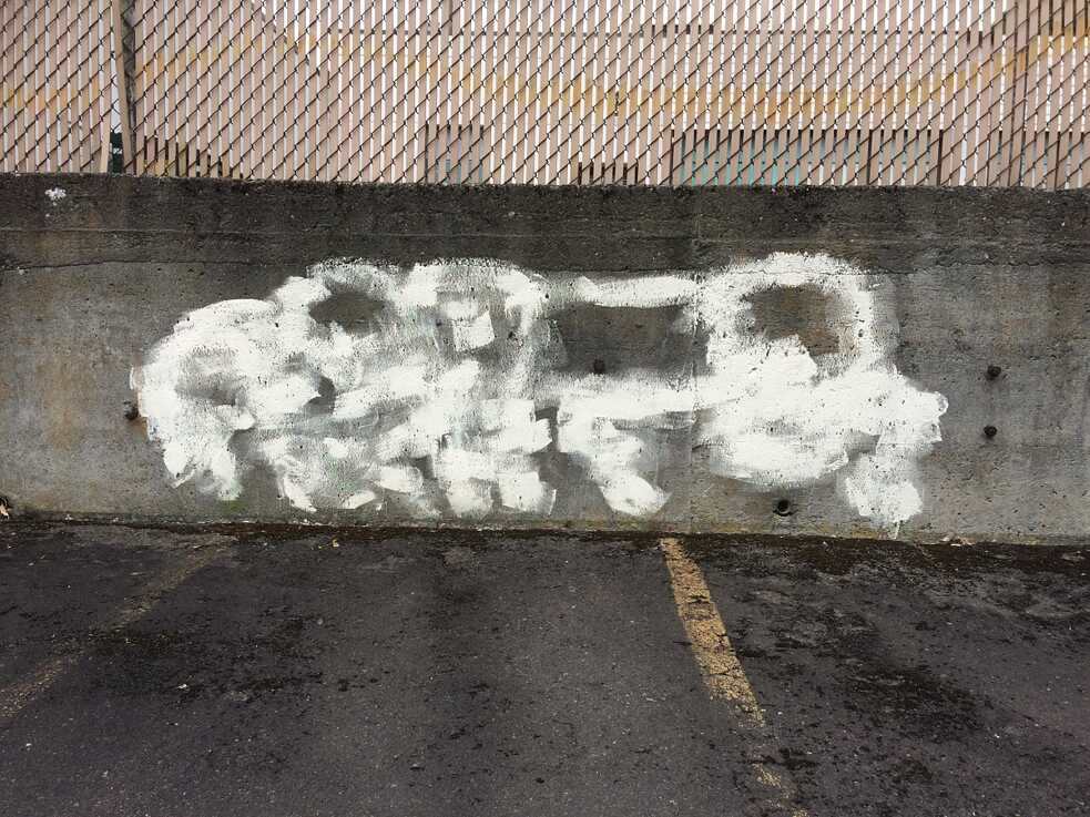 Die unbewusste Kunst der Graffiti-Entfernung: Ein schabloniert übermalter „ghosted“-Tag (Tag = grafisch gestaltete Graffiti-Signatur).