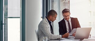 Zwei Geschäftsmänner arbeiten sich durch Unterlagen