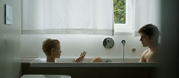 Filmo „Žuvis, plaukianti prieš srovę“ scena, vonioje vienas priešais kitą sėdi moteris ir vyras