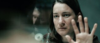 Naine seisab  teisel pool läbipaistvat klaasseina