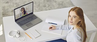 Young woman at desk with headphones and laptop