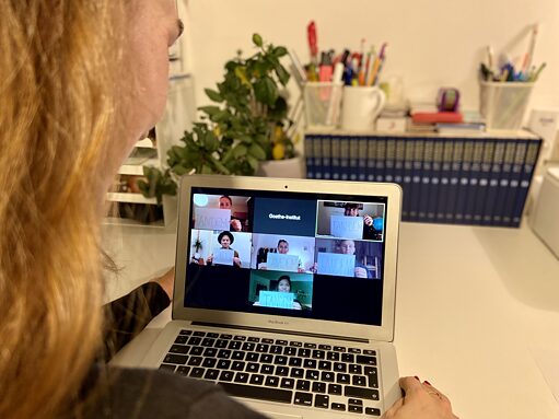 Frau guckt auf Laptop mit Teilnehmern einer Videokonferenz