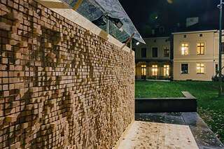 Im Innenhof steht eine Wandinstallation aus Plexiglasgerüst, in das Holzklötze mit eingravierten Zitaten eingesetzt sind.