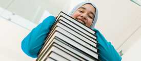 Frau lehnt auf einem Bücherstapel