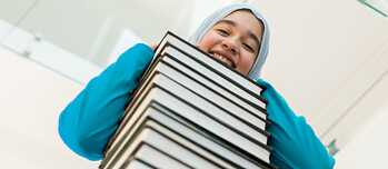 Frau lehnt auf einem Bücherstapel