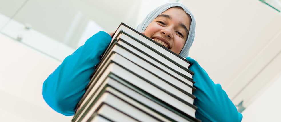 Frau lehnt auf einem Bücherstapel