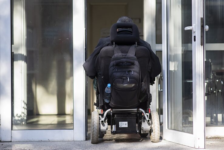 Мъж в инвалидна количка влиза през врата