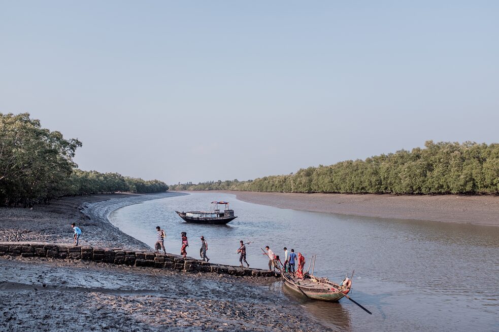 Die Gezeitenströme reichen bis in die nördlichen Sundarbans, Dutzende Meilen von der Küste entfernt. Hier überqueren Einheimische bei Ebbe den Fluss Datta. Sadhupur, Indien. 2019.