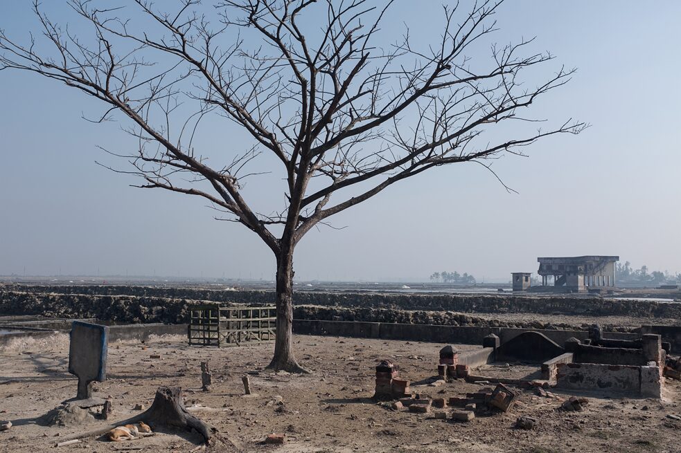 After the hurricane: In the foreground the ruins of a cemetery, behind it the remains of a shelter. Matarbari, Bangladesh. 2020.
