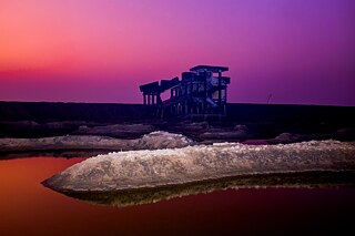 Behind the new dam is the ruin of a village school. Cranes in the distance stand on the building site for a power station. Matarbari, Bangladesh. 2020.