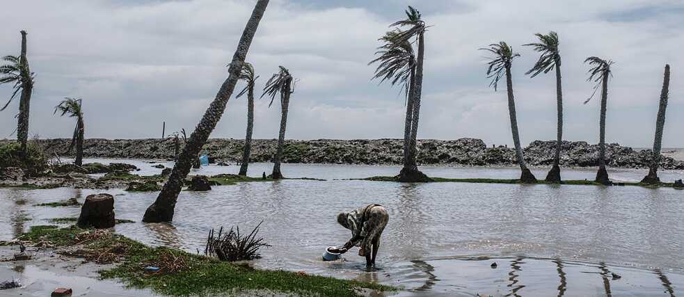 A woman does her washing on the site where her house stood until a protective dam broke, Sagar Island, India 2019 